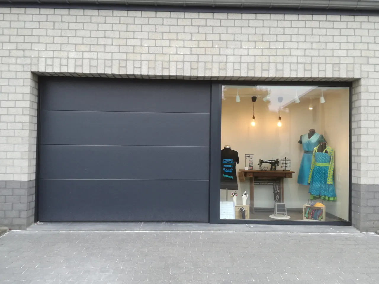 Antraciet sectionale garagepoort naast een etalageraam