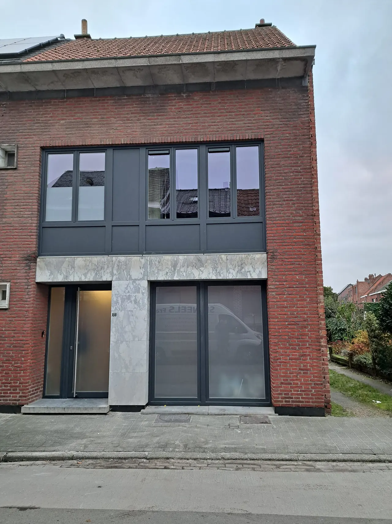 Gerenoveerde bakstenen gevel met antraciet ramen, voordeur en gevelpanelen