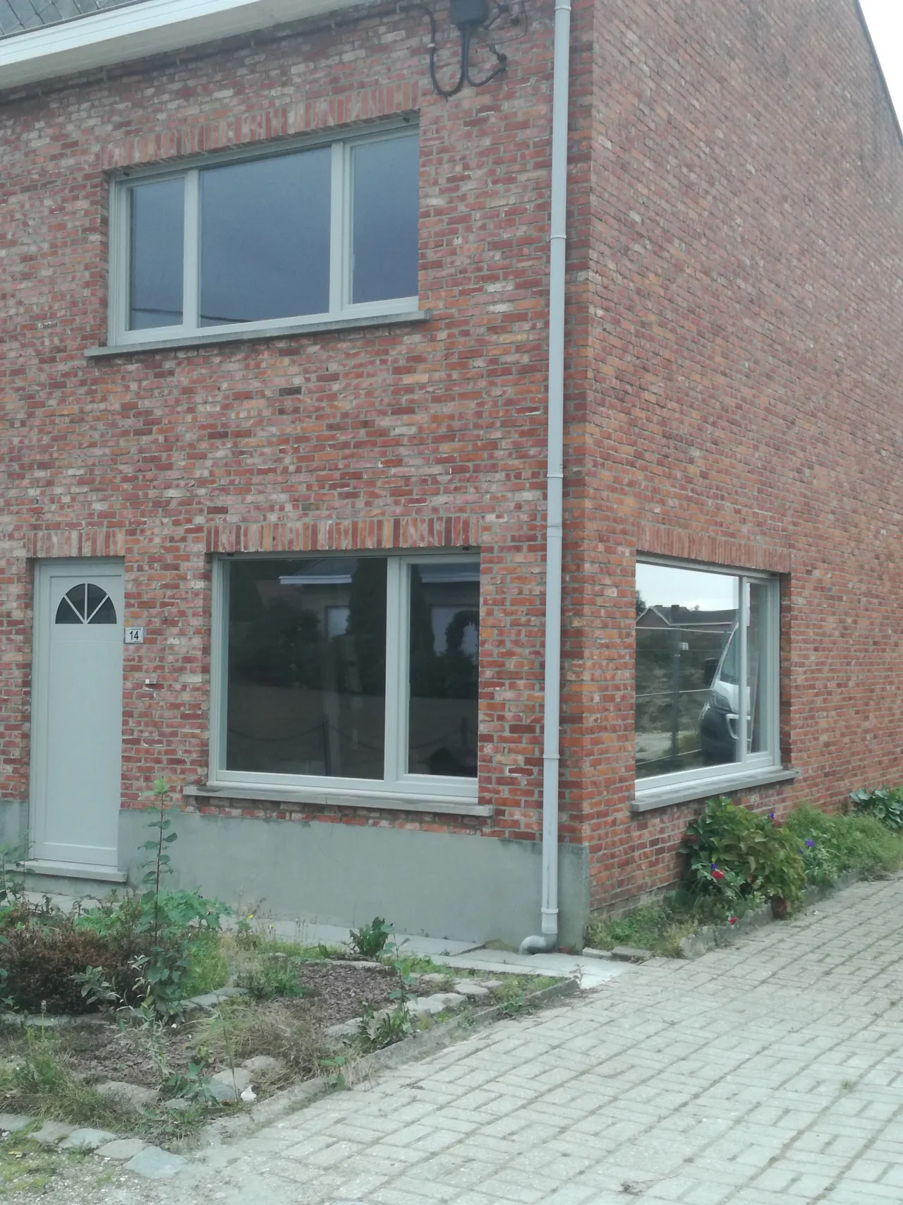 Bakstenen woning met grijze ramen en een bijpassende voordeur