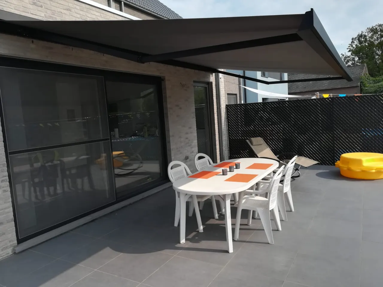 Terras met grote schuiframen en een uitgerold knikarmscherm