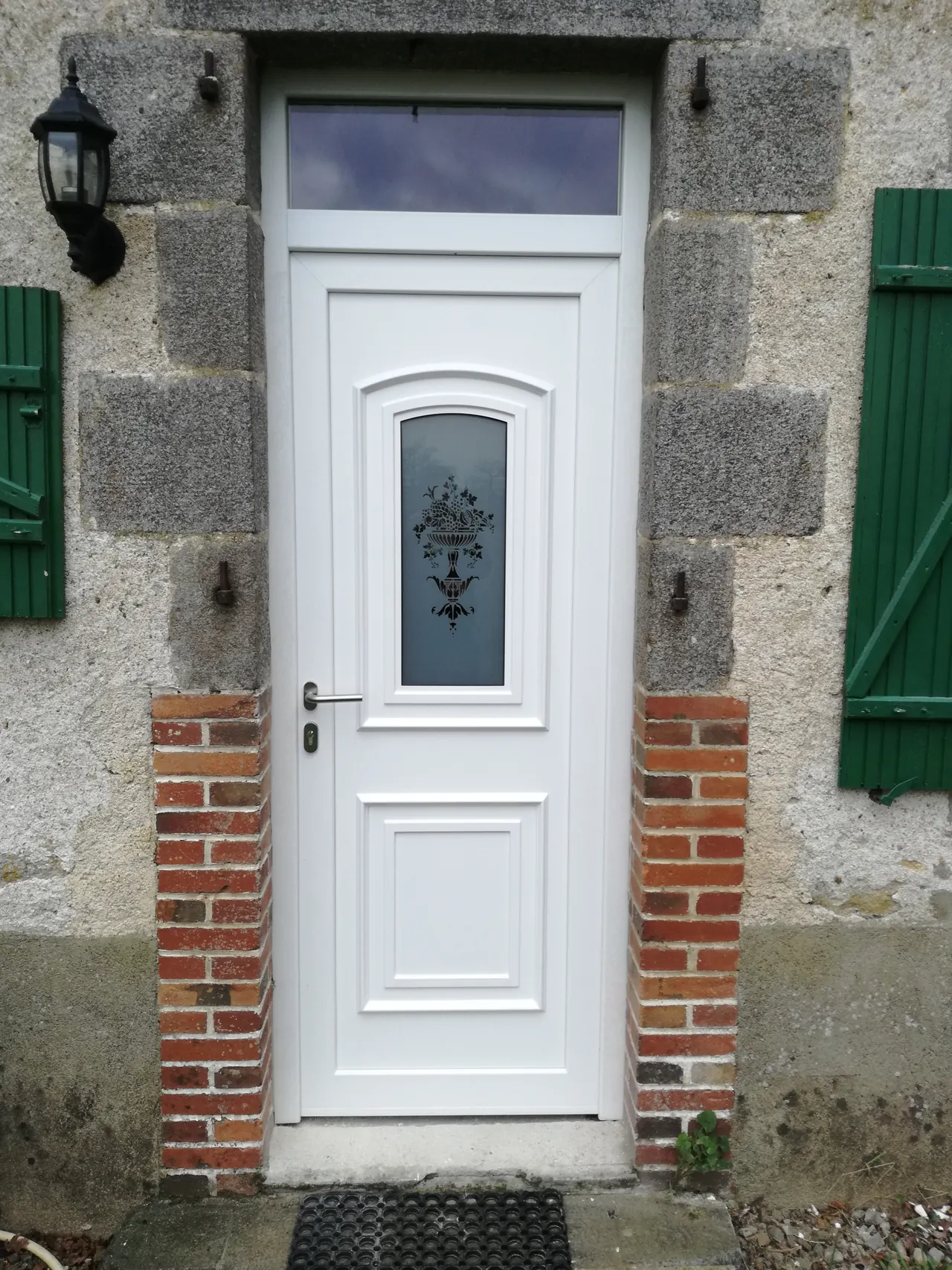 Witte pvc-voordeur met glasdecor in een oude stenen gevel