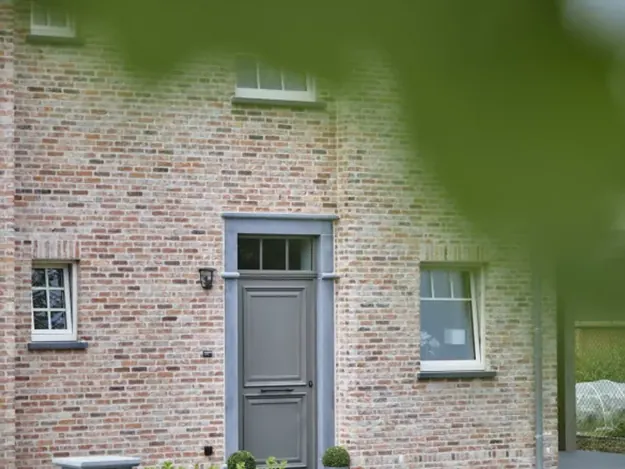 Landelijke gevel met Centric pvc-ramen en een grijze voordeur