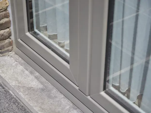 Detail van een vlak Qubic pvc-raam in een natuurstenen gevel